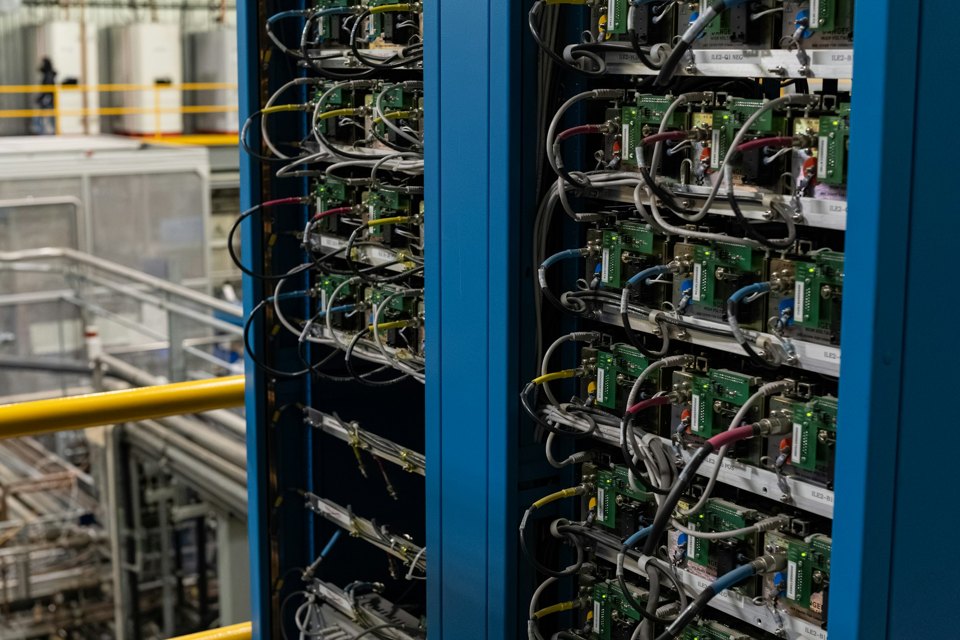 Two blue server racks with dense cabling, illustrating a controlled API platform migration.
