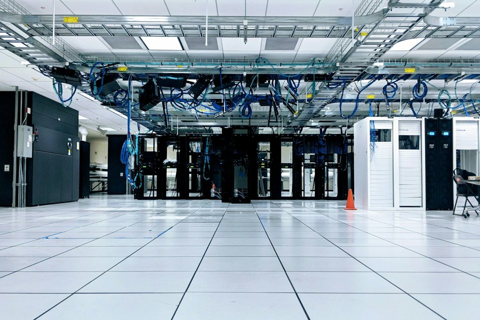 Bright data center with server cabinets and overhead network cables, illustrating Apache Tomcat production infrastructure.